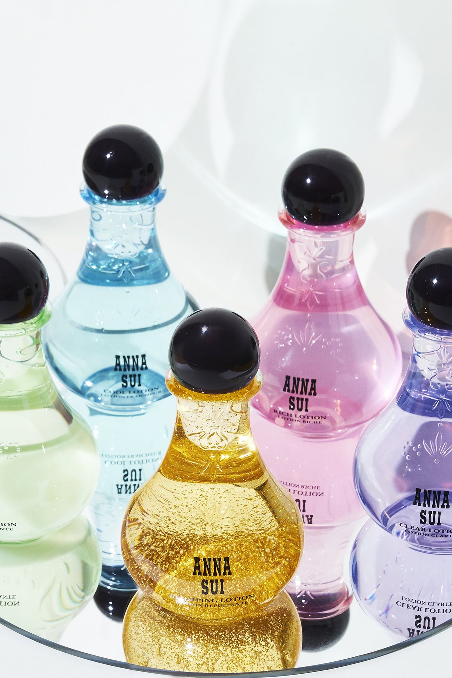 5-bulb-shaped containers, Plumping, Clear. Rich, Cool, and smoothing Lotion, on a round glass tray